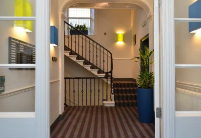 Entrance lobby with an elegant arched staircase and blue accent planters.
