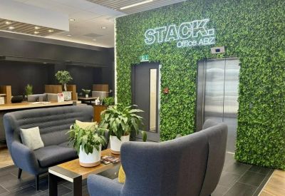 Reception area with a green moss wall, blue armchairs, and wood-topped coffee table.