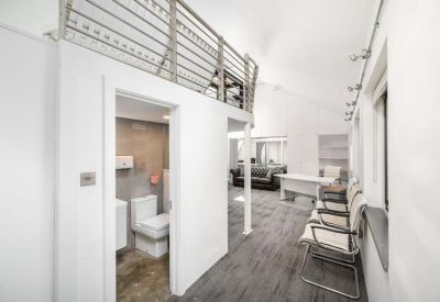 A modern restroom with white tiling and an upper mezzanine balcony overlooking the area.