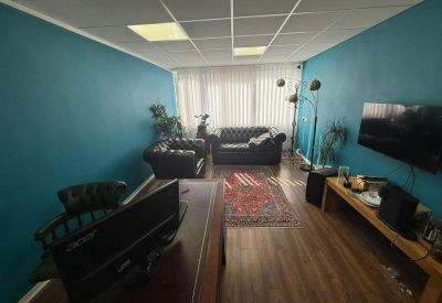 Private office featuring teal walls, leather sofas, a patterned rug, and a large desk.