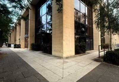Exterior corner of a professional building with light stone pillars and large glass window panels.