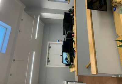 Bright, modern open-plan office with multiple computer workstations and white ceilings.