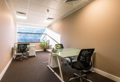 Quiet two-person private office suite with glass-top desks and a large window.