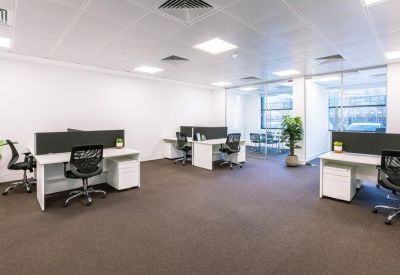 Spacious open office area with white desks and black ergonomic chairs.
