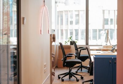 Modern workspace with ergonomic chairs and a minimalist neon wall light.