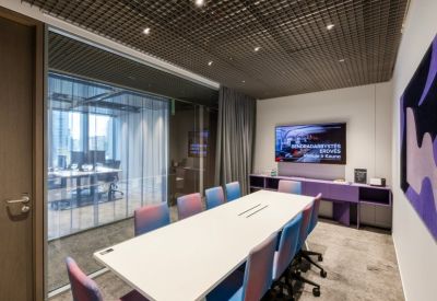 Modern boardroom with a long white table and vibrant blue and purple chairs.