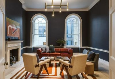 Formal meeting room with dark walls, red sofa, and large arched windows.
