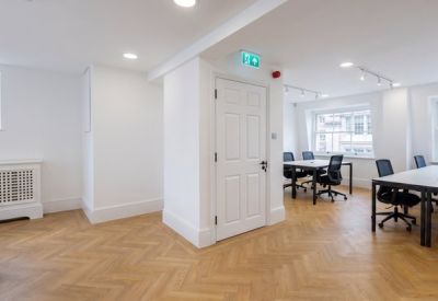 Spacious open office area with white walls and natural light from multiple windows.