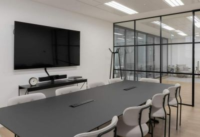 Modern conference room with a black table, grey chairs, and a glass partition wall.