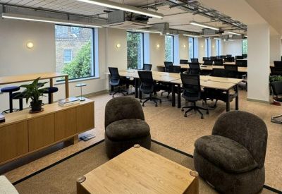 Bright open-plan workspace featuring rows of wooden desks and modern office chairs.