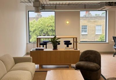 Lounge area featuring a long cream sofa, wooden table, and dark armchairs.
