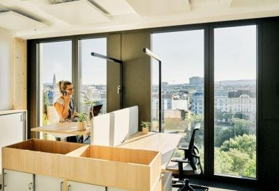 Bright workspace featuring height-adjustable desks and floor-to-ceiling windows.