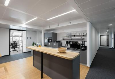 Close-up of a contemporary office kitchen area with a wooden breakfast bar and coffee amenities.