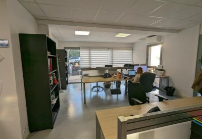 Brightly lit shared workspace with wooden desks and ergonomic office chairs.