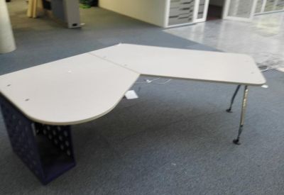 L-shaped white corner desk with blue storage base in an open office area.