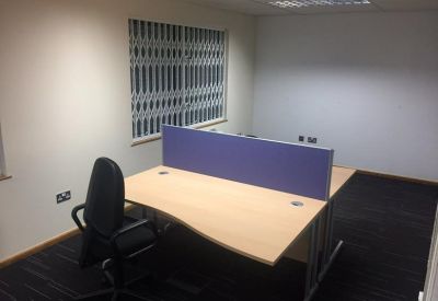 Small private office suite with a two-person desk and security shutters on the window.