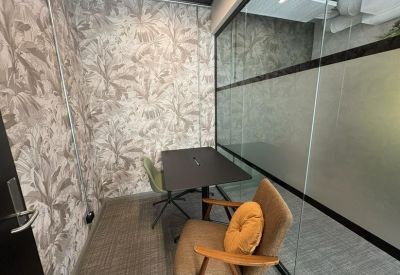 Small private focus room with tropical wallpaper, a black desk, and a comfortable armchair.