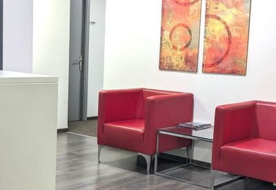 Reception area with a warm wood desk and bright abstract art on the walls.