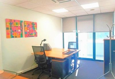 Modern office workstation with an orange desk and a view of a city street through a glass door.