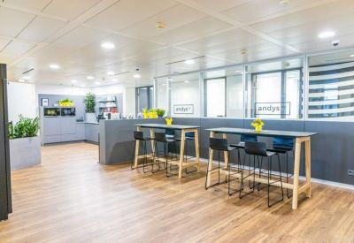 Communal break area with high tables, bar stools, and kitchenette access.