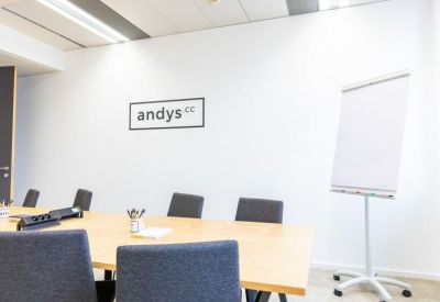 Bright meeting room with a large wooden table and flipchart.