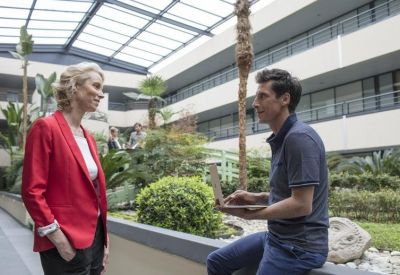 Internal courtyard garden with lush plants and two colleagues talking under a skylight.