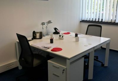 Private office suite with white desks, black ergonomic chairs, and blue carpeting.