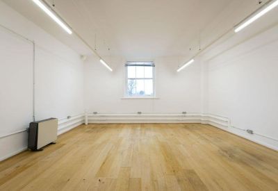 Spacious empty studio with polished light wood floors and white walls.