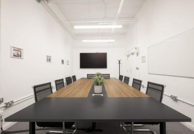 Professional boardroom with a long wood-topped table and wall-mounted screen.