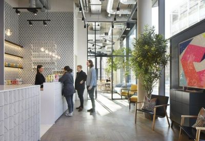 Bright reception area with white tiled desk, vibrant abstract art, and indoor trees.