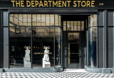 Close-up of the black storefront entrance featuring gold signage and display mannequins.