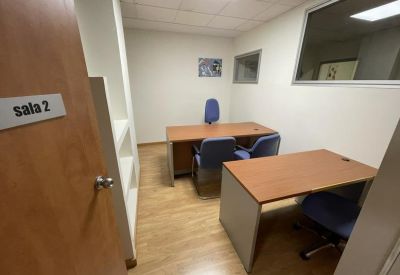 Private three-person office with wooden desks and blue chairs.