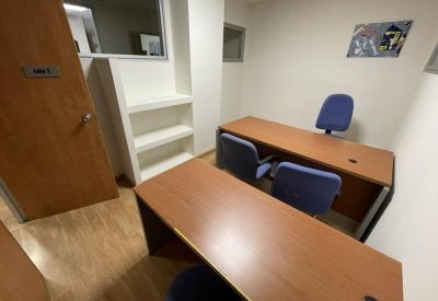 Internal office suite with built-in white shelving and wooden flooring.