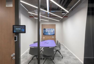 Colorful seating area with purple armchairs next to large windows.