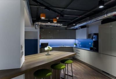 Modern kitchen and breakout area with a wooden island and green bar stools.