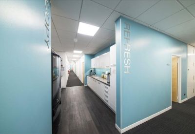 A light blue breakout area labeled Refresh with a modern kitchenette and long hallway.