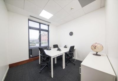 Bright private office with white desks, black chairs, and a large window.