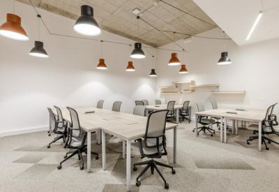 Bright coworking space with multiple desks and modern hanging lamps.