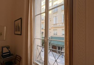Tall French window with a Juliet balcony looking out onto Parisian architecture.