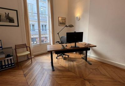 Bright workspace with ornate ceiling molding and a large window overlooking the street.