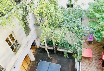 Overhead view of a central courtyard with a ping-pong table and lush greenery.