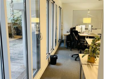 Bright hallway workspace with long glass windows and desk pods.