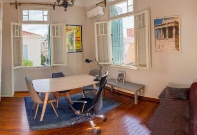 Bright workspace with a white table, blue rug, and large windows with shutters.