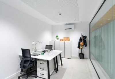 Bright private office suite with two white desks, ergonomic black chairs, and a glass partition wall.