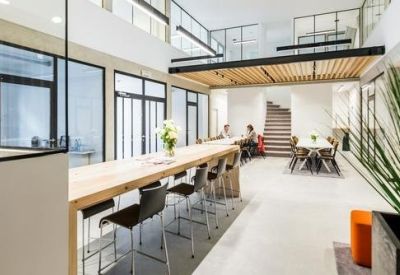 Bright communal dining area with long wooden tables and indoor greenery.