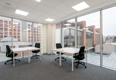 Minimalist two-desk private office with floor-to-ceiling windows and city views.