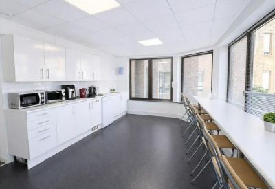 Clean communal kitchen area with white cabinetry, microwave, and integrated bar seating.
