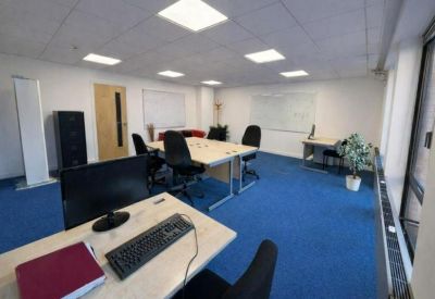 Naturally lit workspace with a central cluster of desks and a whiteboard.