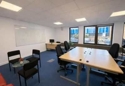 Professional meeting area with a glass coffee table, black chairs, and large windows.