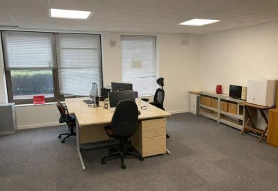 Well-lit office area with desks, storage shelving, and built-in ceiling lighting.